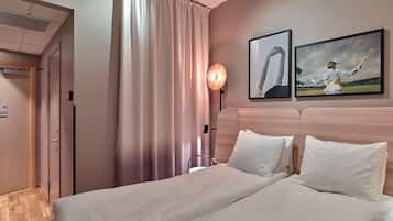 A hotel room with a bed, a nightstand, a lamp, and two framed pictures on the wall.