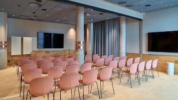A conference room with rows of chairs, a large screen, and a pillar.