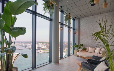 A modern interior with large windows, a sofa, and potted plants.