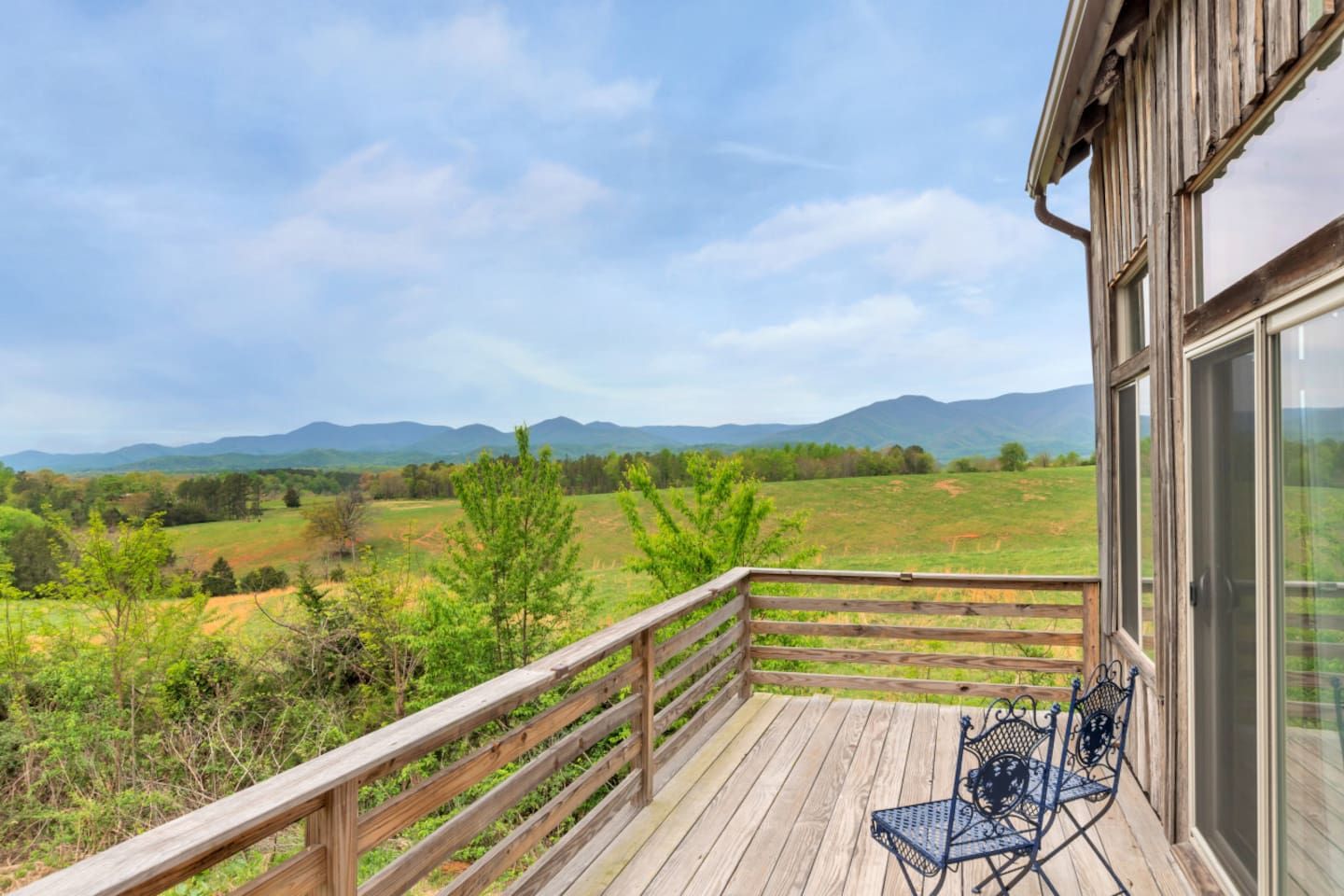 Eine Holzterrasse mit Blick auf eine grüne Landschaft und Berge.