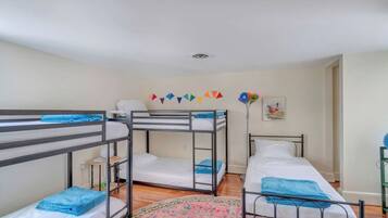 Un dormitorio con camas literas, una mesita de noche pequeña, una lámpara y una alfombra colorida.
