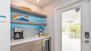 Una cocina compacta con cafetera, licuadora y refrigerador con puerta de vidrio.