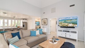 Una sala de estar moderna con un sofá color beige, una mesa de centro de madera y un televisor de pantalla plana montado en un mueble blanco.
