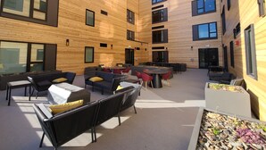 A modern outdoor seating area with wooden paneling, tables, and chairs.
