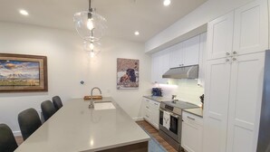 A modern kitchen with white cabinets, stainless steel appliances, and a central island.