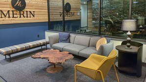 A modern interior with a wooden wall, a sofa, a yellow chair, a coffee table, and a lamp.