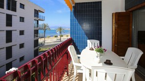 A balcony with a white table, chairs, and a potted plant. - PLAYAZUL 2 Apartment (Cambrils)