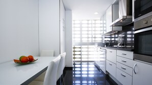 Uma cozinha moderna com armários brancos, bancada preta e janela com padrão geométrico.