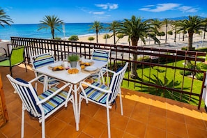 A balcony with a table set for breakfast, overlooking a beach and palm trees. - Sea Views  4 Bedrooms  Pool (Cambrils)