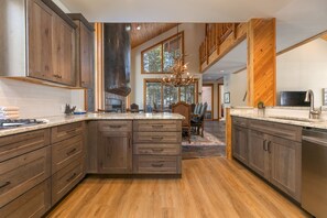 A spacious kitchen with wooden cabinets, a large island, and a chandelier.