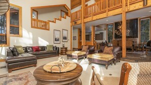 A spacious living area with a high ceiling, wooden staircase, and large windows. - Grand Antler Lodge: Spacious, Updated, Sleeps 16 (Breckenridge)