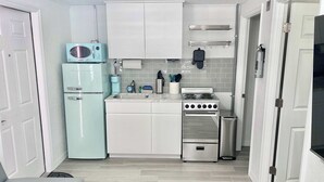 A compact kitchen with white cabinets, a light blue refrigerator, a stove, and a sink. - Newly Renovated Charlotte Harbor - Sunset Inn #5 (Port Charlotte)