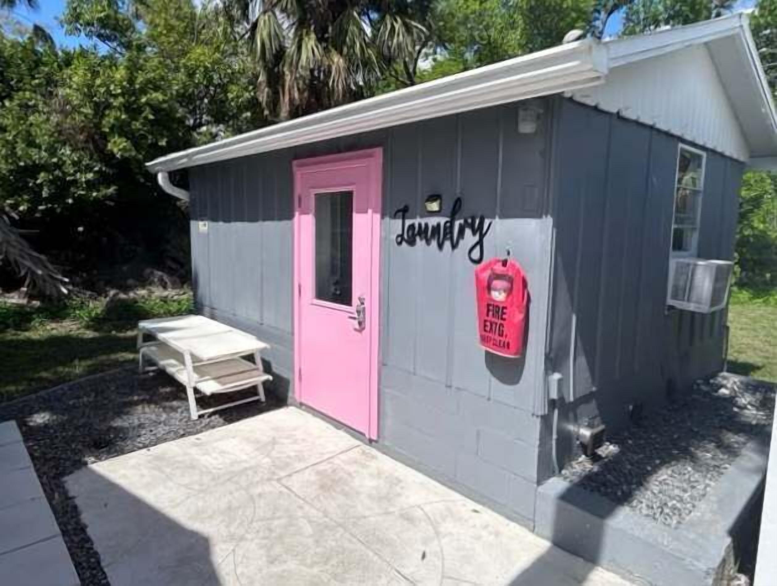 A small laundry facility with a pink door and a fire extinguisher mounted on the wall.