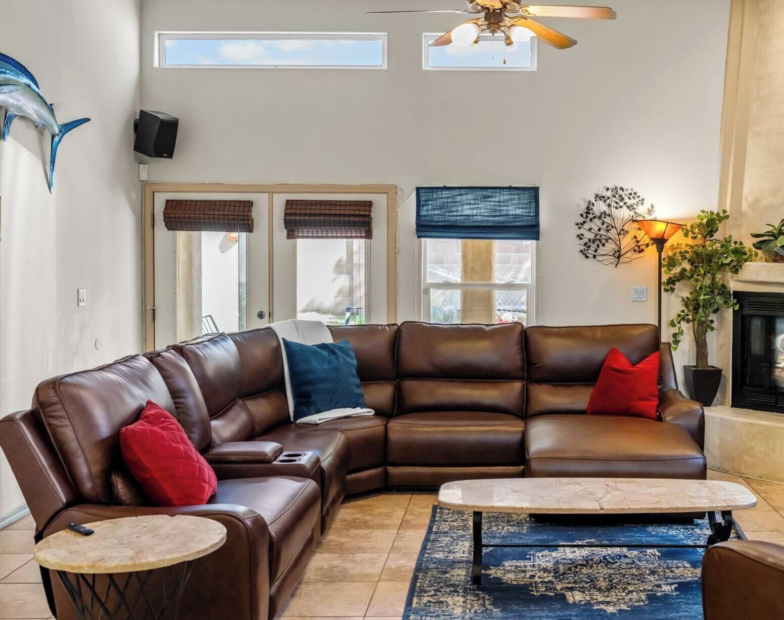 A living room with a brown leather sectional sofa, a small round coffee table, and a fireplace.