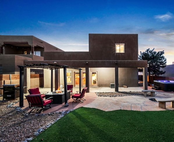 Una casa moderna con un patio, mobiliario exterior y una chimenea.