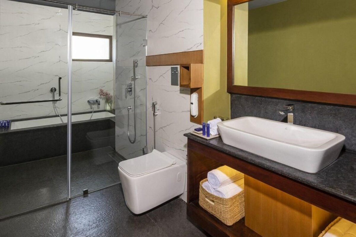 Un baño moderno con cabina de ducha de vidrio, lavamanos blanco y un espejo grande.