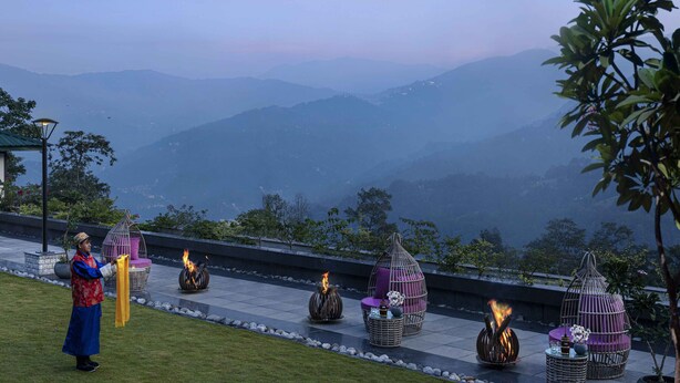Um terraço com área de estar externa, lareira e vista para montanhas distantes.
