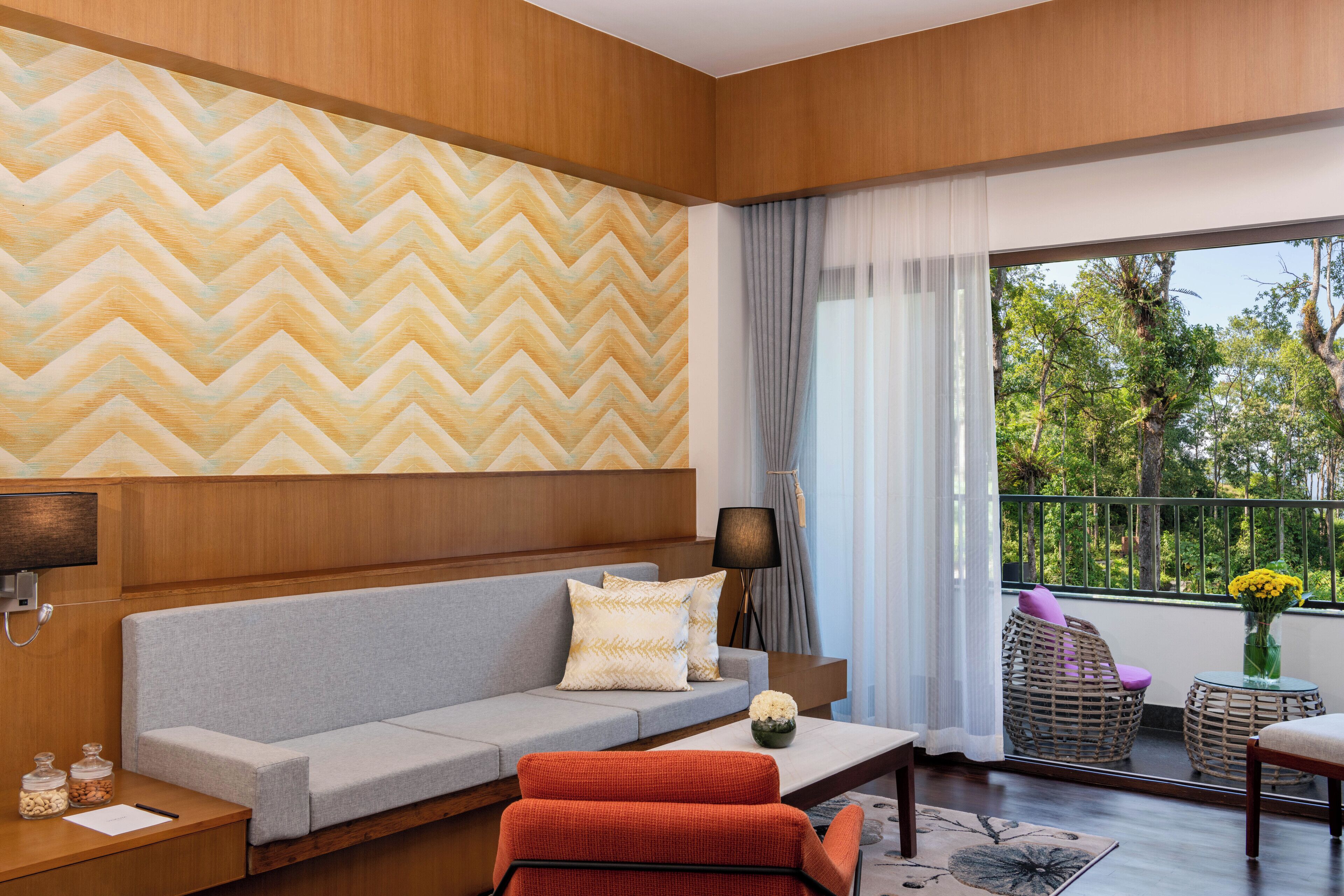 Una sala moderna con un sofá gris, un sillón rojo y suelo de madera.