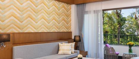 Una sala moderna con un sofá gris, un sillón rojo y suelo de madera.