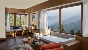 Uma sala de estar moderna com uma janela grande, um sofá, uma área de jantar e vista para as montanhas.