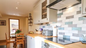 A modern kitchen with a wooden countertop, stainless steel appliances, and a tiled backsplash. - Little Gem (Uttoxeter)