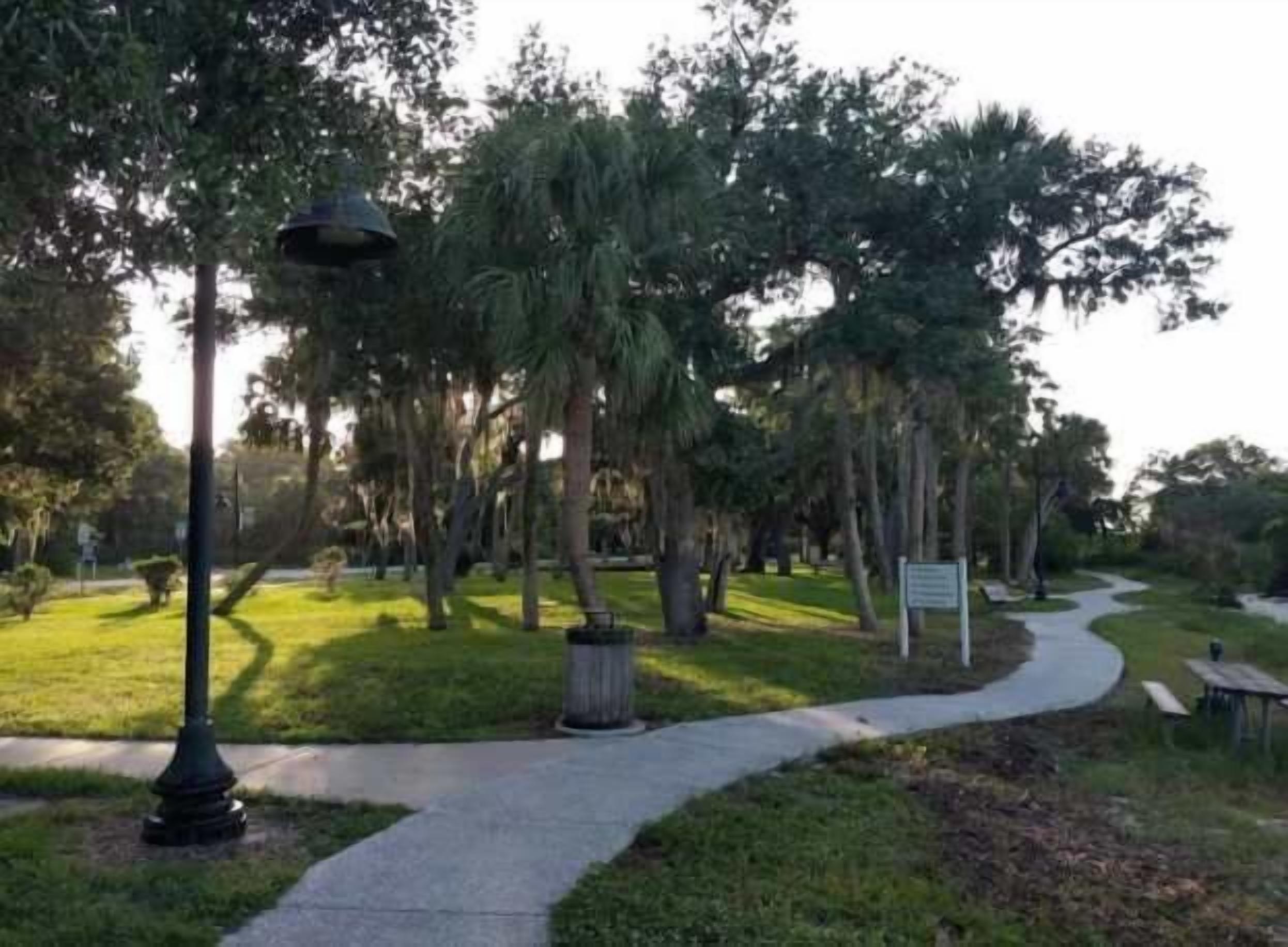 A park pathway with trees and a lamp post.
