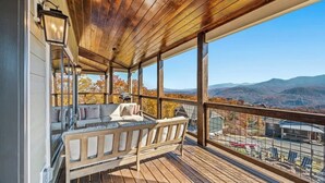A wooden deck with a bench, a view of mountains, and a clear sky.