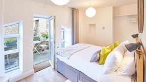 Un dormitorio con cama, lámpara de noche y vistas al exterior.