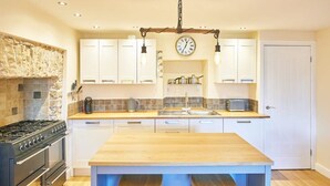 Una cocina con armarios blancos, una isla de madera, un salpicadero de piedra y una estufa negra.