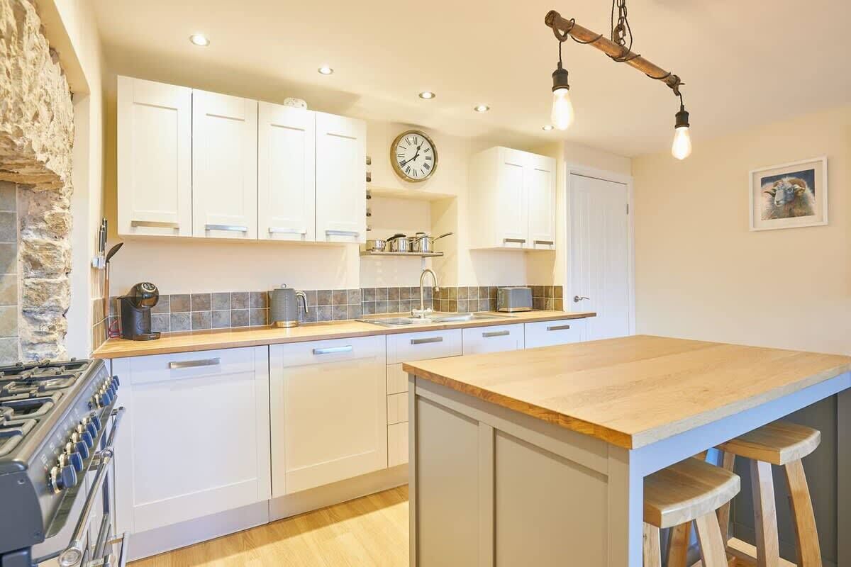 A kitchen with white cabinets, a wooden countertop, a gas stove, and a hanging light fixture.