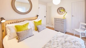 Un dormitorio con cama, lámparas de noche, cómoda, silla y espejo.