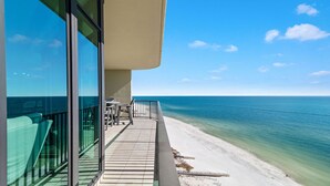 Ein Balkon mit Blick auf den Ozean, einen Sandstrand und einen klaren Himmel.