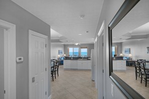 A modern kitchen with a central island, white cabinetry, and a view of the ocean through large windows.