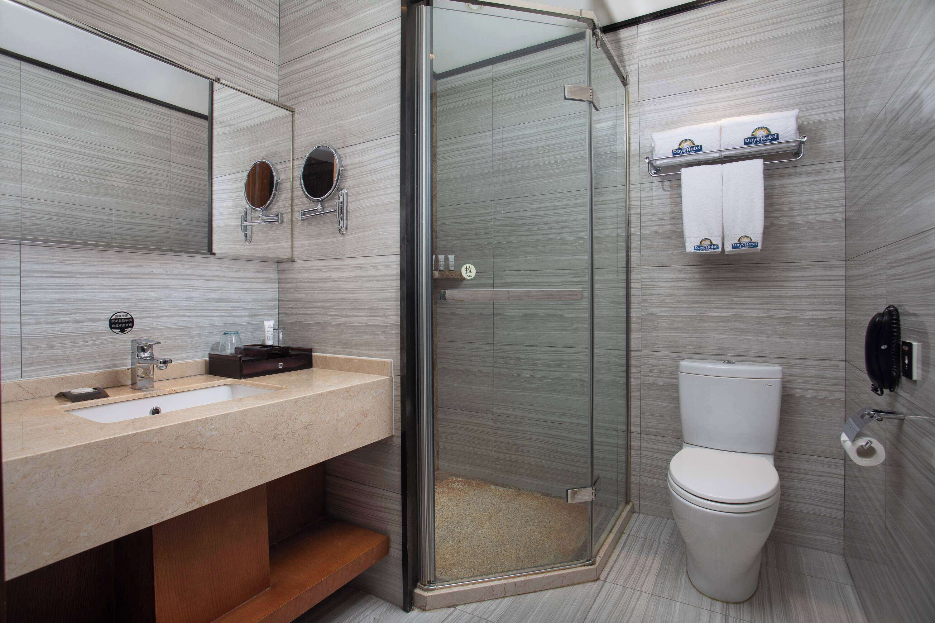 Un baño moderno con ducha de vidrio, un lavabo con espejo y un inodoro.