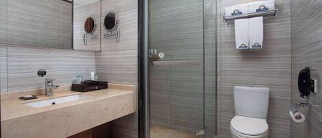 Un baño moderno con ducha de vidrio, un lavabo con espejo y un inodoro.