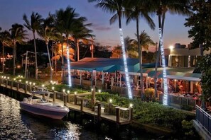 A waterfront restaurant with a dock, palm trees, and a boat. - Spacious Private Pool Oasis (Delray beach)