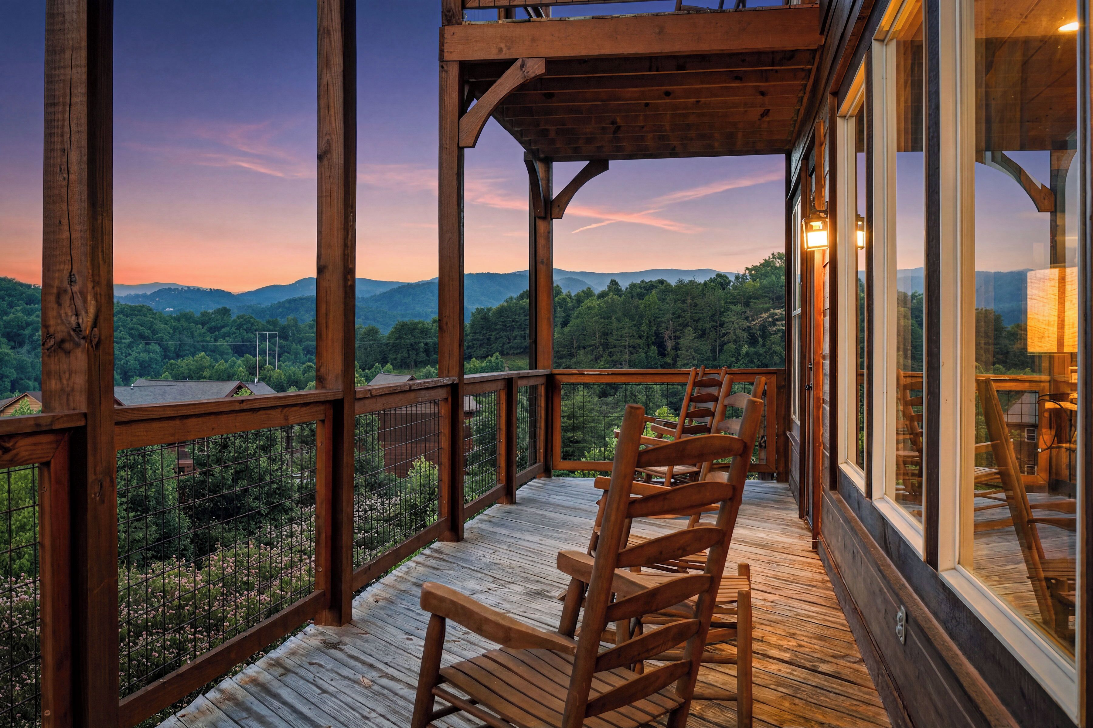 Una terraza de madera con sillas, con vistas a un paisaje boscoso y montañas a lo lejos.