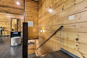 Um interior em madeira com escadaria, área de bar e espaço para sentar.