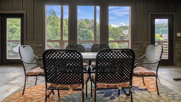 A conference room with a large table, four chairs, and large windows with a view of trees and buildings.
