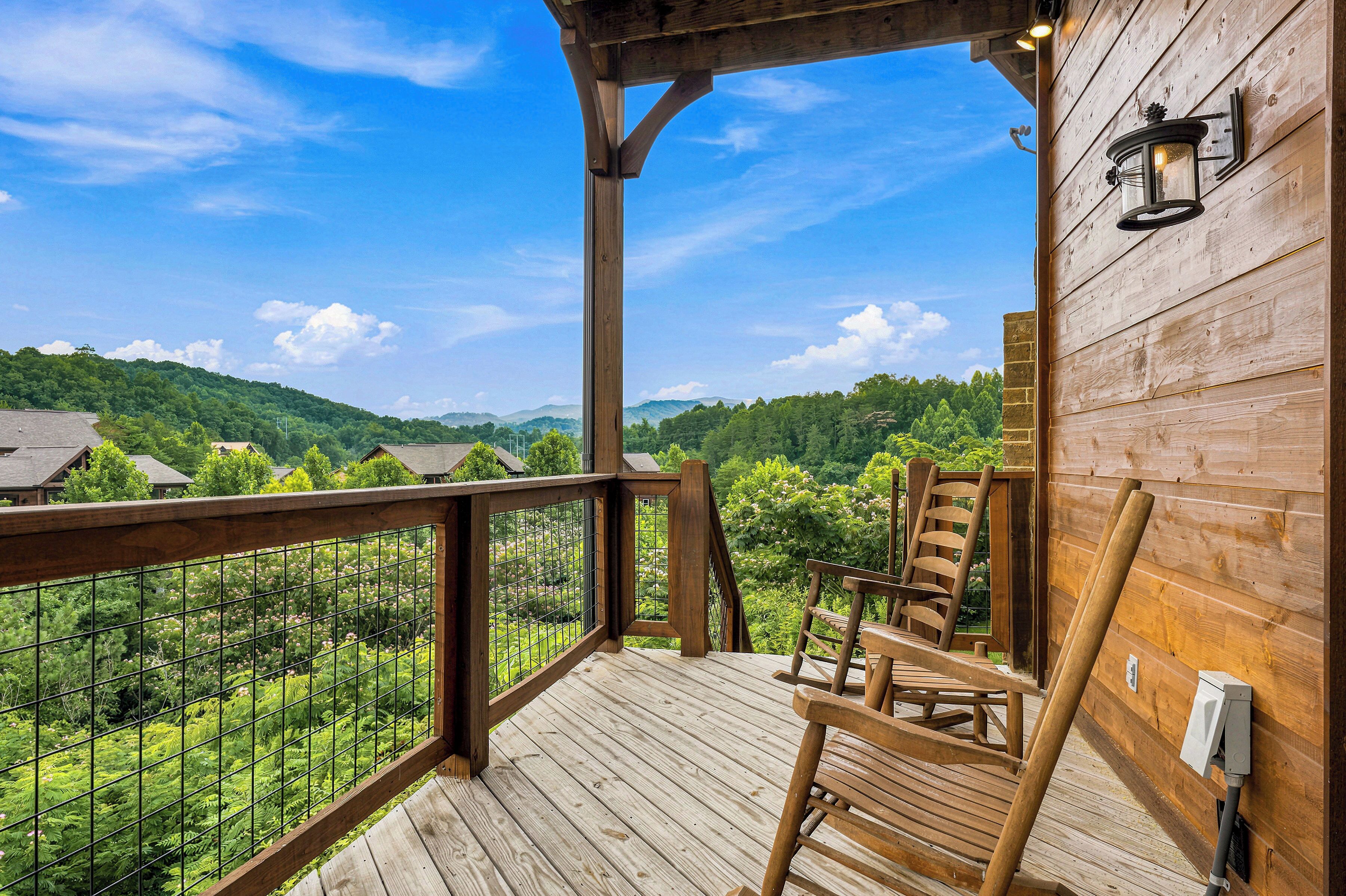 A wooden deck with a view of a forested mountain range.