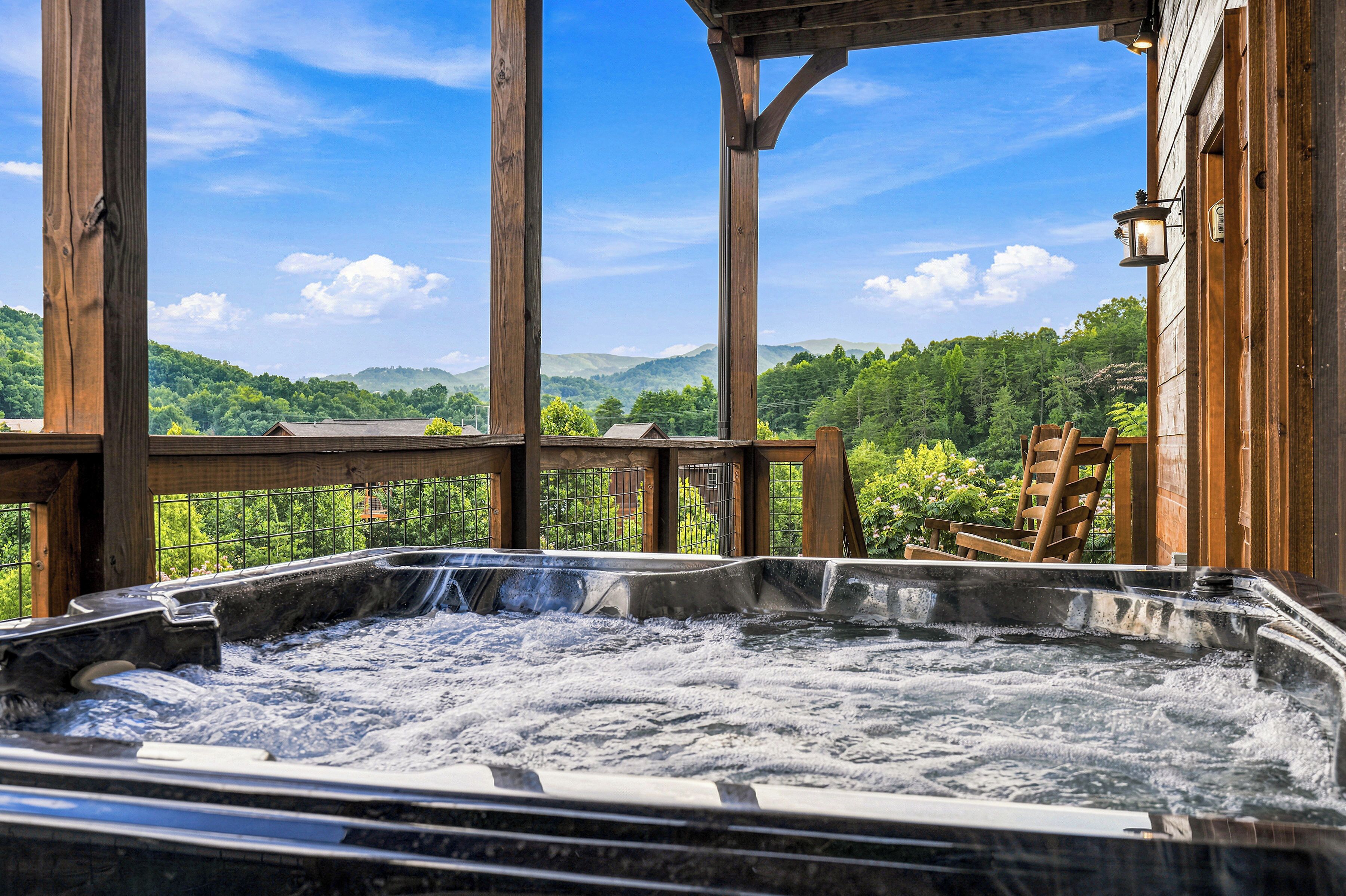 Een hottub met een houten terras en uitzicht op een bebost landschap.
