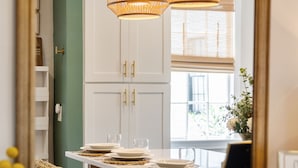 A dining area with a table set for four, a mirror reflecting the room, and a hanging light fixture. - The Charleston Suites: The Emerson Suite (Charleston)