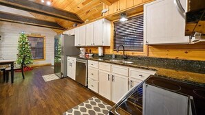 A modern kitchen with wooden cabinets, a granite countertop, and a built-in stove. - The Busy Beaver Lodge (McCurtain County)