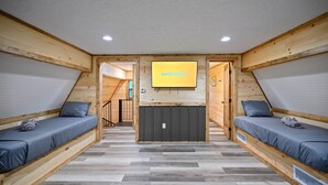 Une pièce avec deux lits superposés, un plafond en bois et un écran de télévision fixé au mur qui affiche le mot « performance ».