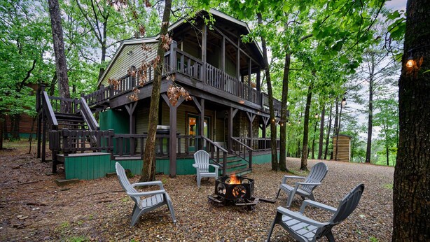 Une cabane dotée d’une terrasse, de meubles de jardin et d’un foyer extérieur.