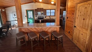 L’intérieur d’un chalet en bois comprend une cuisine, des tabourets de bar et une grande porte en bois.