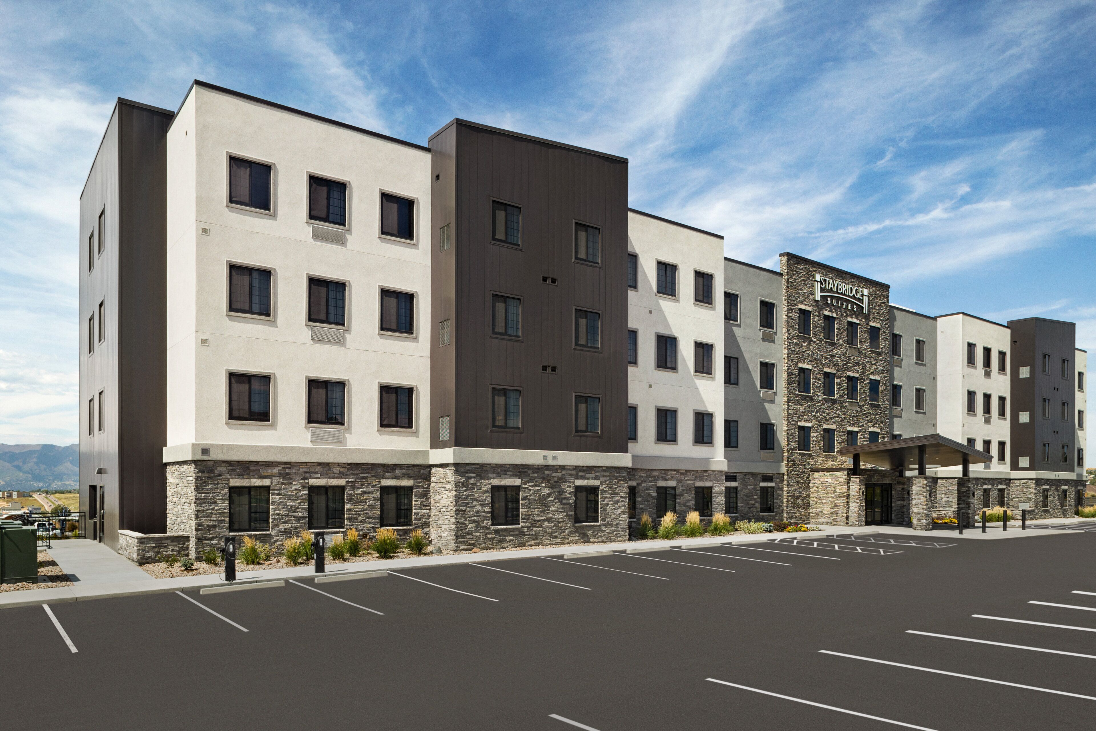 A multi-story hotel with a modern design, featuring a stone facade and a covered entrance.