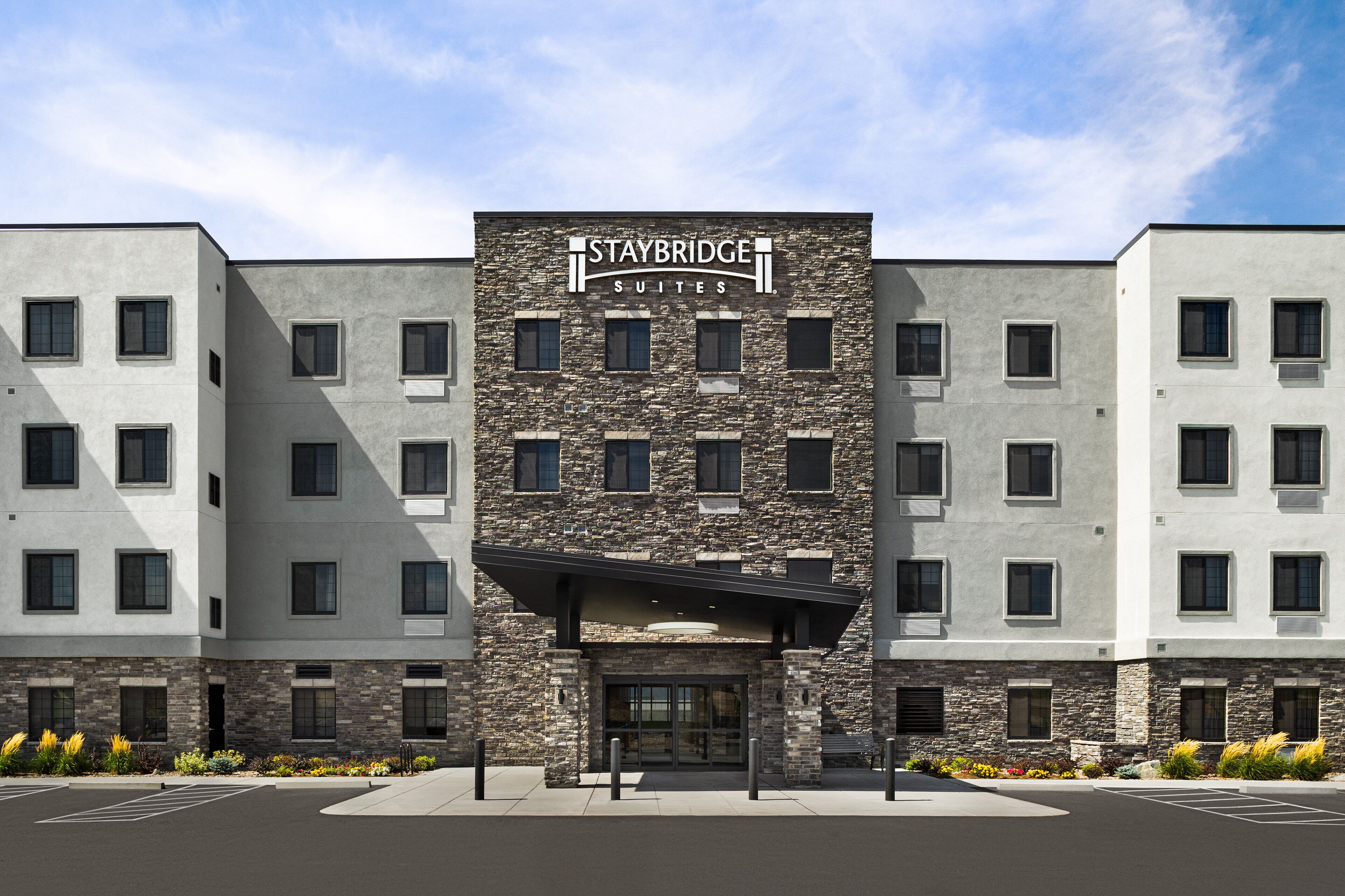 A Staybridge Suites hotel with a stone facade, multiple windows, and a covered entrance.