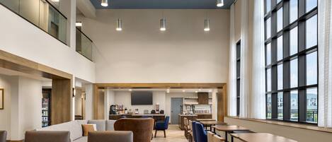 A spacious indoor area with multiple seating arrangements, a kitchen area, and large windows providing natural light.