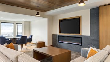 A modern living room with a fireplace, comfortable seating, and a large TV mounted on the wall.